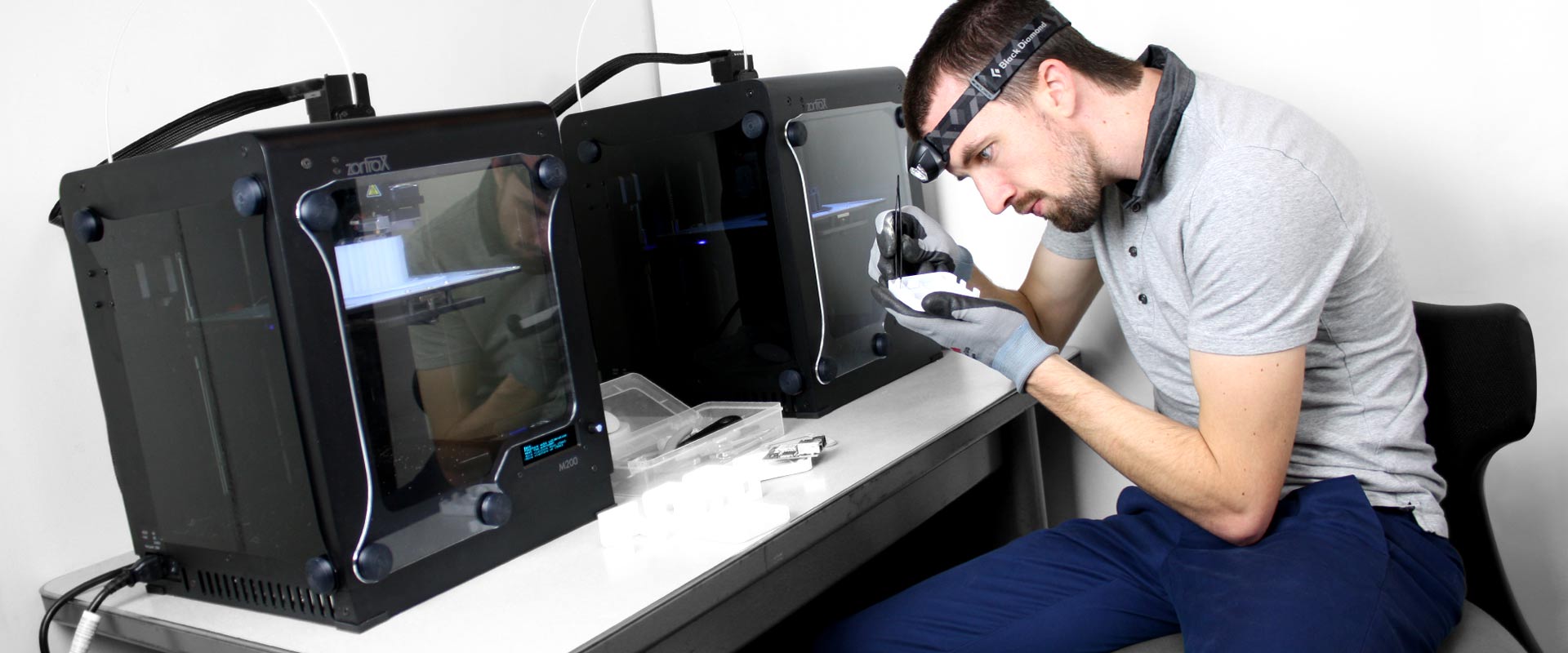 Josh working on a 3D printed model in front of his 3D printing machines