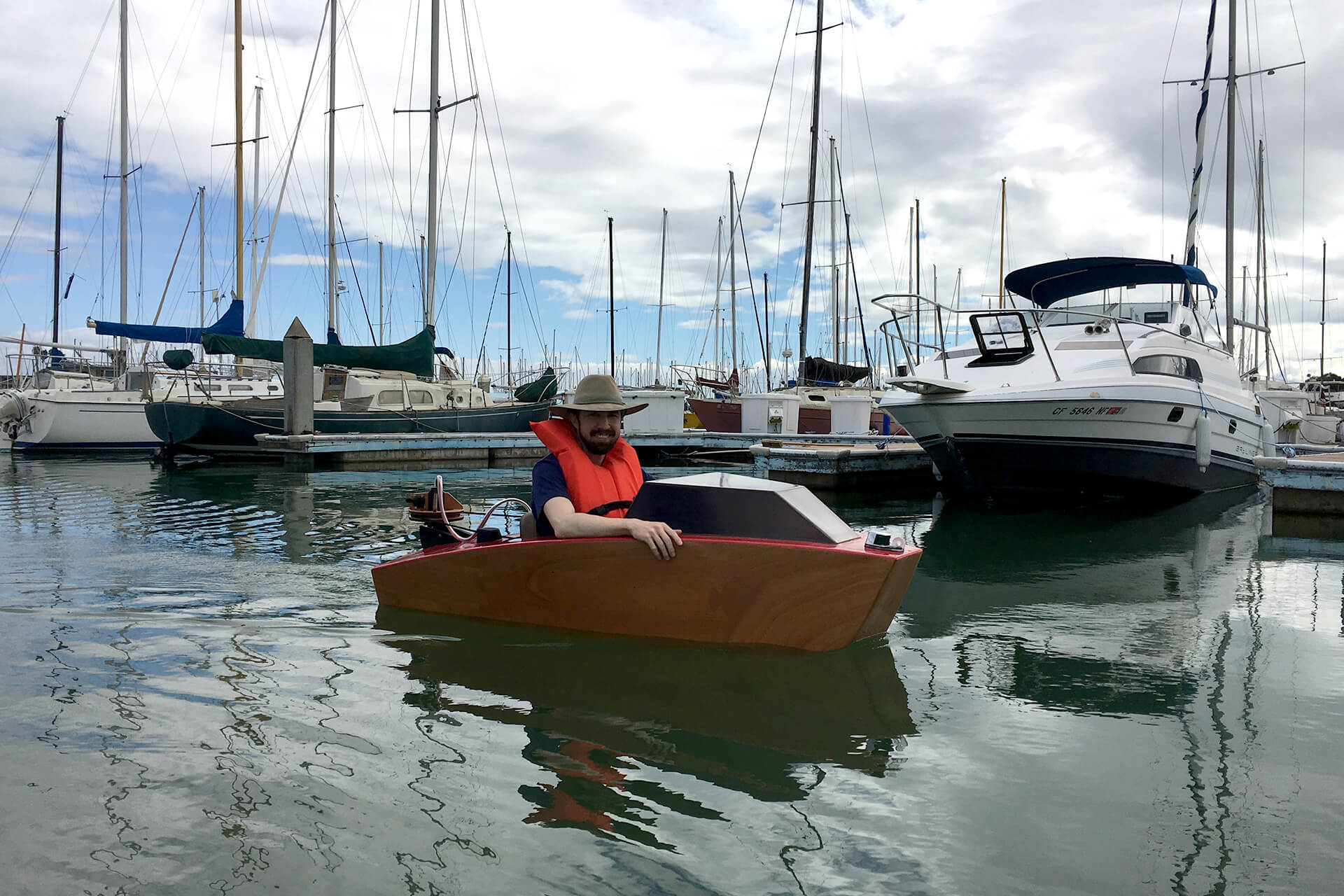 A mini boat cruising in the Emeryville harbor on a calm day