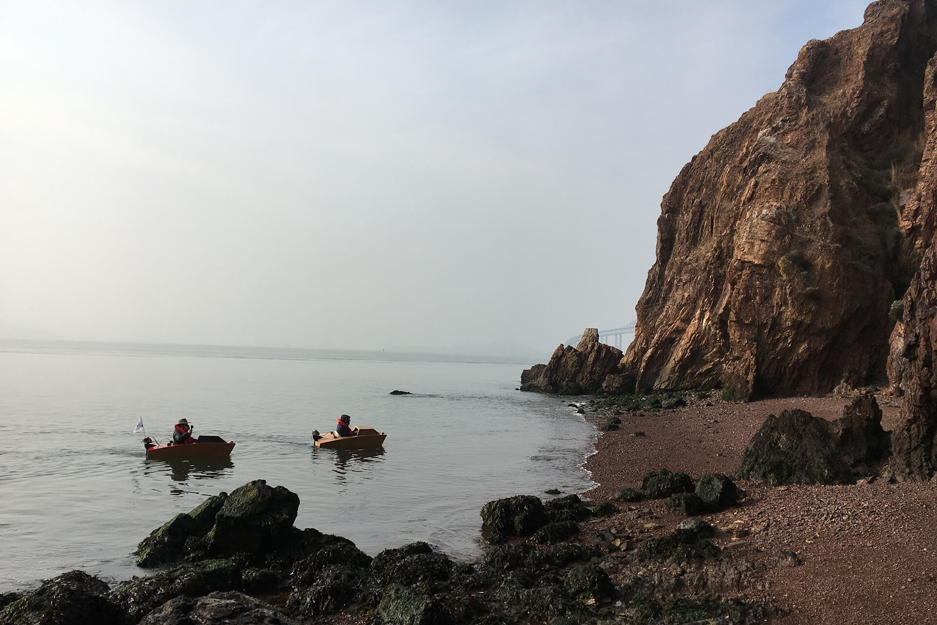 Two mini boats about to land on the shore of red rock island